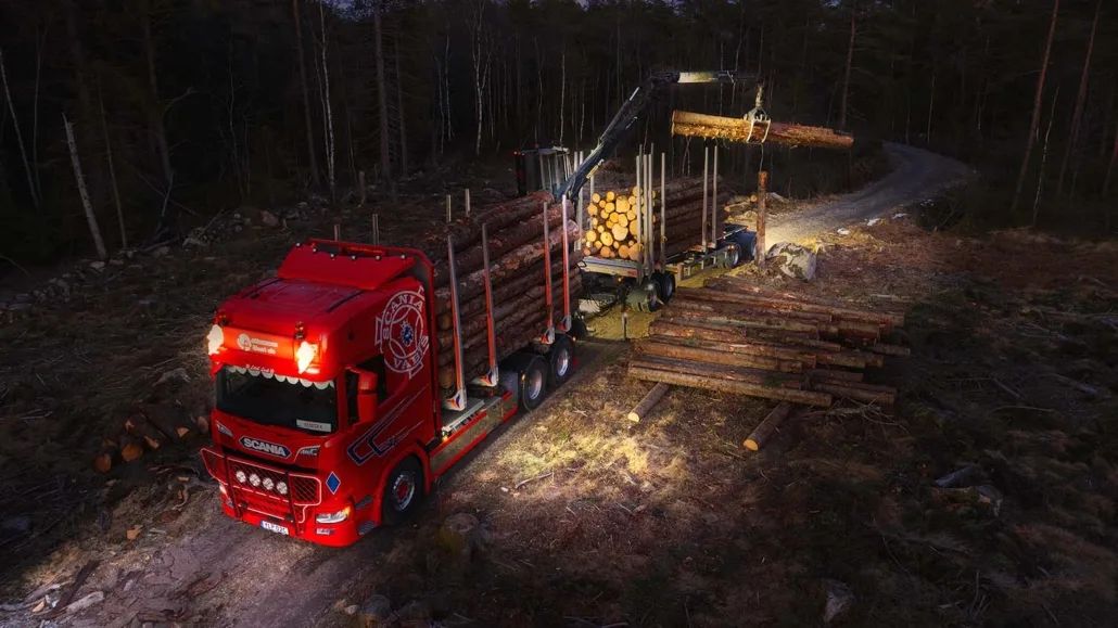 Scania logging truck from Ottossons Åkeri equipped with TYRI LED work lights loading timber at night in a forest, ensuring maximum visibility and safety.