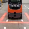 Close-up of a vehicle equipped with TYRI VL4 RedLine LED lights, projecting a sharp red safety line onto the ground to indicate danger zones and enhance workplace safety.