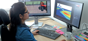 Our 3D Visualisation Artist Dipti, sits at a desk looking at a computer screen showing simulations for off-highway work lights.