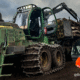 Forestry forwarder loaded with logs working on rugged terrain in a rural landscape, equipped with TYRI LED work lights for visibility, with an inset image of machine operator; Ben Wade, in high-visibility workwear