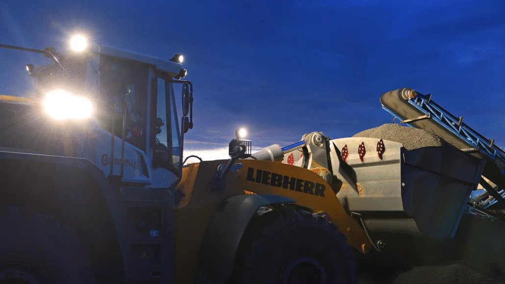 Liebherr wheel loader operating in a quarry at dusk, equipped with TYRI 1010 Hi-CRI LED work lights providing bright, natural illumination for enhanced visibility and safety.
