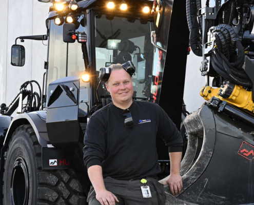 Christopher Kindblom in front of his well-maintained Huddig machine equipped with INTELLilight, used in an Optoschakt project.